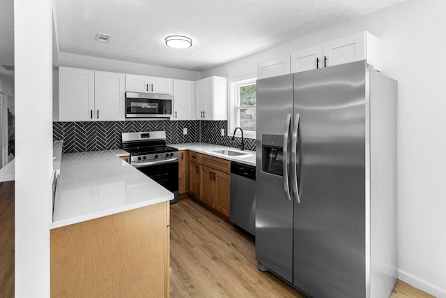 70 5th Ave SW, Etna, OH 43062 - kitchen featuring stainless steel appliances, a sink, light wood-style flooring, backsplash, and white cabinets