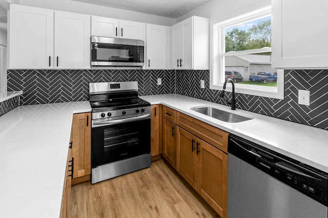 70 5th Ave SW, Etna, OH 43062 - kitchen with stainless steel appliances, a sink, light wood-style floors, light countertops, and white cabinetry