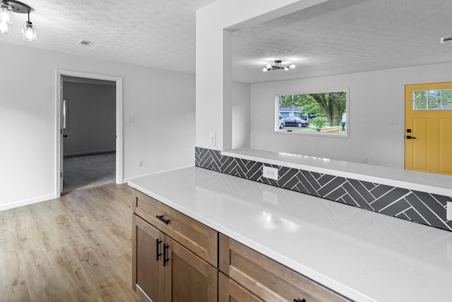 70 5th Ave SW, Etna, OH 43062 - kitchen with light wood-style flooring, light countertops, a textured ceiling, backsplash, and brown cabinetry
