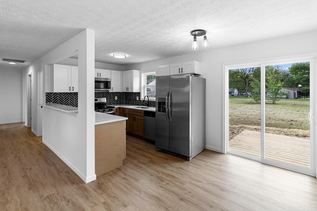 70 5th Ave SW, Etna, OH 43062 - kitchen with appliances with stainless steel finishes, a sink, light wood-style floors, tasteful backsplash, and a textured ceiling