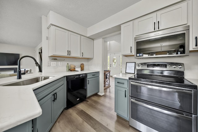 1779 Westwood Dr, Lewis Center, OH 43035 - kitchen with stainless steel appliances, a sink, light wood-style flooring, light countertops, and a textured ceiling