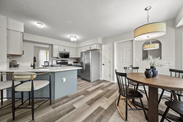 1779 Westwood Dr, Lewis Center, OH 43035 - kitchen featuring stainless steel appliances, a peninsula, a breakfast bar, light wood-type flooring, and light countertops
