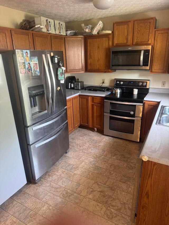 1539 Fuller Ct, Lancaster, OH 43130 - kitchen with appliances with stainless steel finishes, brown cabinetry, stone tile flooring, and a textured ceiling
