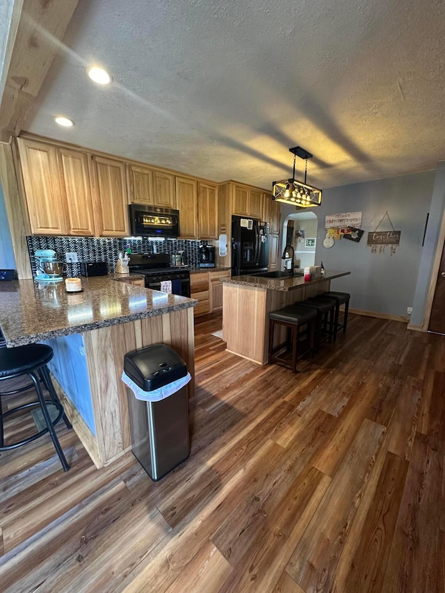 4902 Columbus Sandusky Rd N, Marion, OH 43302 - kitchen with black appliances, a textured ceiling, a breakfast bar, dark wood-style flooring, and baseboards