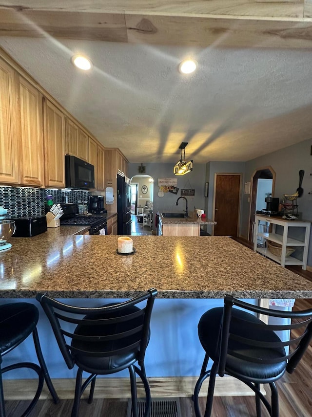 4902 Columbus Sandusky Rd N, Marion, OH 43302 - kitchen with black microwave, a peninsula, gas range oven, a kitchen breakfast bar, and arched walkways