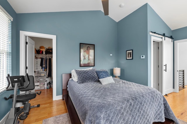 233 S Ohio Ave Unit 11, Columbus, OH 43205 - bedroom featuring lofted ceiling, a spacious closet, a barn door, a closet, and light wood-style flooring