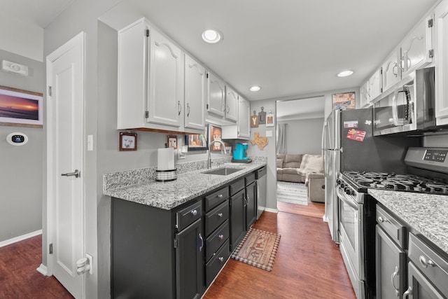 2560 Scioto View Ln, Columbus, OH 43221 - kitchen with appliances with stainless steel finishes, white cabinets, a sink, dark wood-type flooring, and recessed lighting