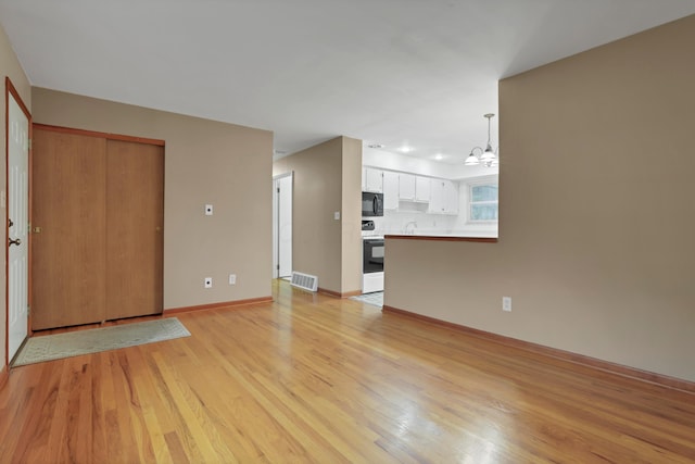 6451 Faircrest Rd, Columbus, OH 43229 - unfurnished living room featuring light wood-style floors, a chandelier, recessed lighting, baseboards, and a sink