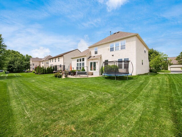 7915 Fargo Ln, Delaware, OH 43015 - rear view of property with stucco siding, a patio area, a trampoline, and a lawn