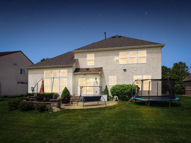 7915 Fargo Ln, Delaware, OH 43015 - back of house featuring a trampoline, stucco siding, a patio area, and a lawn