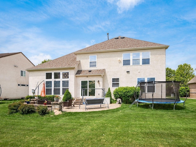 7915 Fargo Ln, Delaware, OH 43015 - back of house with a trampoline, stucco siding, a patio, a yard, and a shingled roof