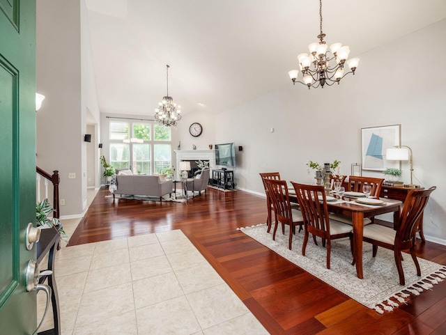 7915 Fargo Ln, Delaware, OH 43015 - dining space with a chandelier, high vaulted ceiling, tile patterned flooring, a fireplace, and baseboards