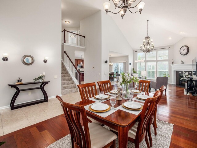 7915 Fargo Ln, Delaware, OH 43015 - dining area with a chandelier, wood-type flooring, high vaulted ceiling, stairs, and a fireplace