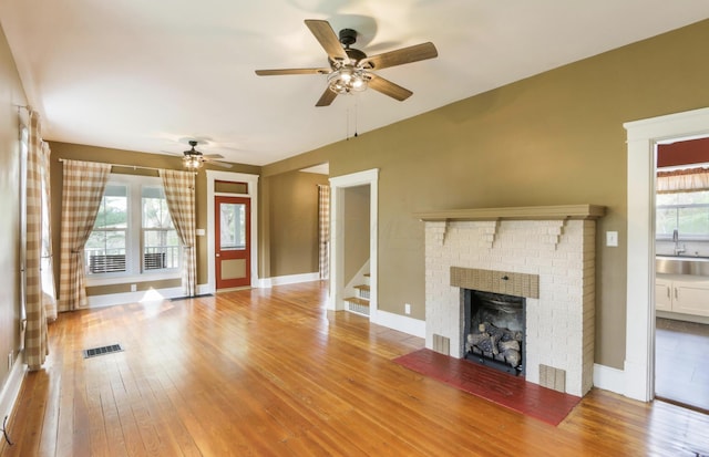 1350 Lancaster Kirkersville Rd NW, Lancaster, OH 43130 - unfurnished living room with hardwood / wood-style flooring, a fireplace, a ceiling fan, a sink, and stairs