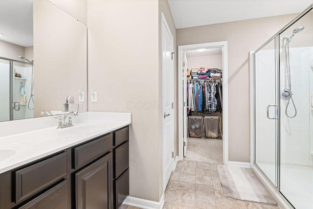 2045 E Gardenia Dr, Pataskala, OH 43062 - bathroom featuring a stall shower, double vanity, a walk in closet, and baseboards