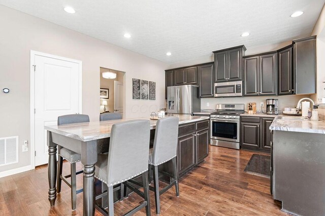 2045 E Gardenia Dr, Pataskala, OH 43062 - kitchen featuring appliances with stainless steel finishes, a sink, a center island, a breakfast bar, and dark wood-style flooring