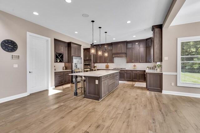 9568 Craigens Ct, Galena, OH 43021 - kitchen with dark brown cabinetry, light countertops, a kitchen breakfast bar, a kitchen island, and recessed lighting