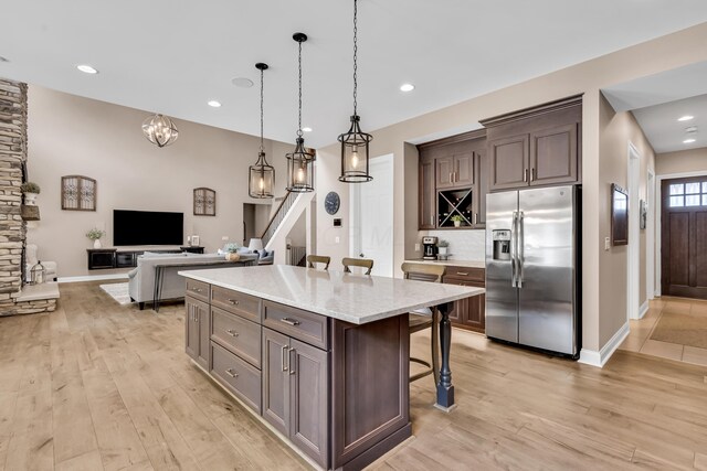 9568 Craigens Ct, Galena, OH 43021 - kitchen featuring stainless steel fridge with ice dispenser, a breakfast bar area, light wood-style floors, a kitchen island, and backsplash