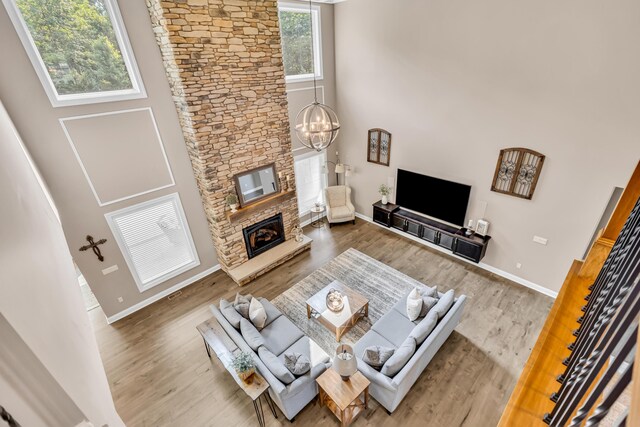 9568 Craigens Ct, Galena, OH 43021 - living area featuring a towering ceiling, wood finished floors, baseboards, a chandelier, and a stone fireplace