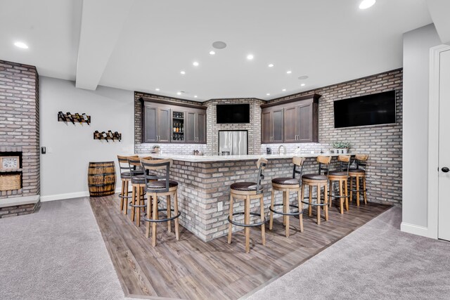 9568 Craigens Ct, Galena, OH 43021 - indoor wet bar with recessed lighting, stainless steel fridge, baseboards, light colored carpet, and brick wall