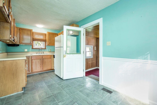 1936 Case Rd, Columbus, OH 43224 - kitchen with a sink, light countertops, a wainscoted wall, freestanding refrigerator, and wooden walls