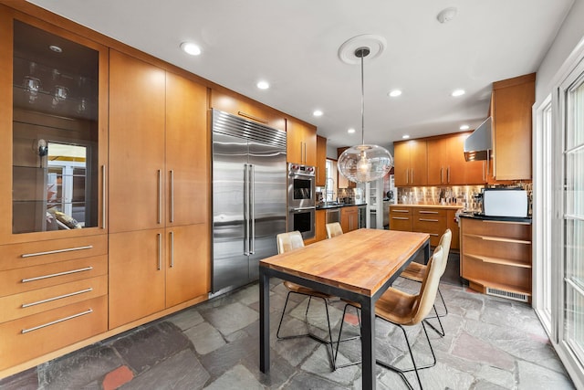 195 S Gould Rd, Columbus, OH 43209 - kitchen with stainless steel appliances, stone tile floors, decorative backsplash, brown cabinetry, and recessed lighting