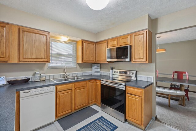 6897 Roundelay Rd N, Reynoldsburg, OH 43068 - kitchen featuring appliances with stainless steel finishes, a sink, dark countertops, and a textured ceiling