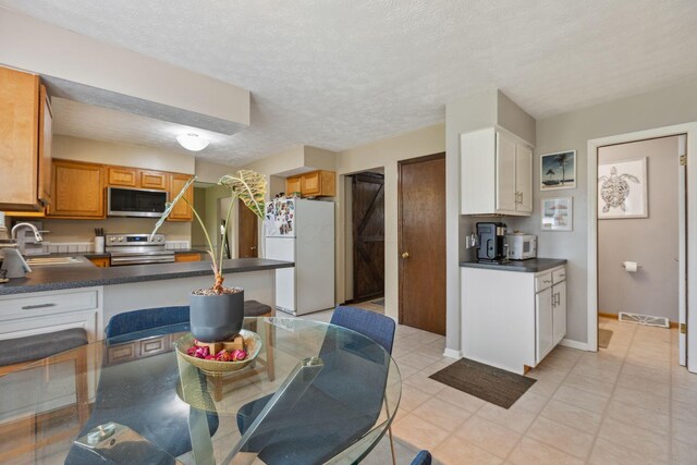 6897 Roundelay Rd N, Reynoldsburg, OH 43068 - kitchen with stainless steel appliances, a sink, dark countertops, a textured ceiling, and a peninsula
