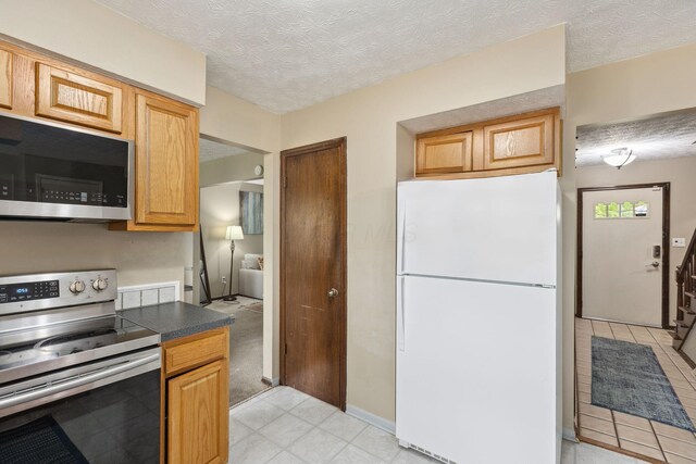 6897 Roundelay Rd N, Reynoldsburg, OH 43068 - kitchen with freestanding refrigerator, electric stove, dark countertops, and a textured ceiling