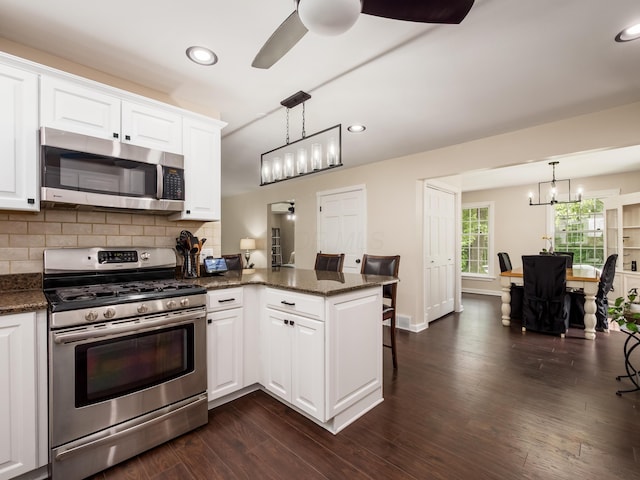 2870 Tarkman Dr, Nashport, OH 43830 - kitchen with stainless steel appliances, a peninsula, a chandelier, white cabinetry, and backsplash