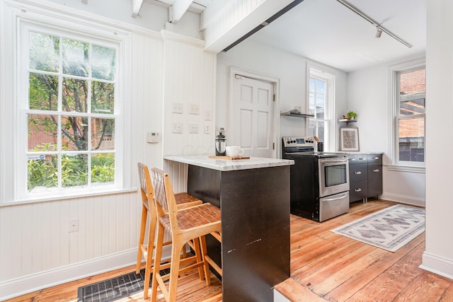 503 City Park Ave, Columbus, OH 43215 - kitchen featuring stainless steel electric range, rail lighting, light wood-type flooring, a kitchen breakfast bar, and open shelves