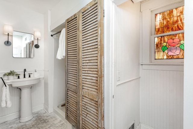 503 City Park Ave, Columbus, OH 43215 - full bathroom featuring baseboards, brick patterned floors, a wainscoted wall, and a shower