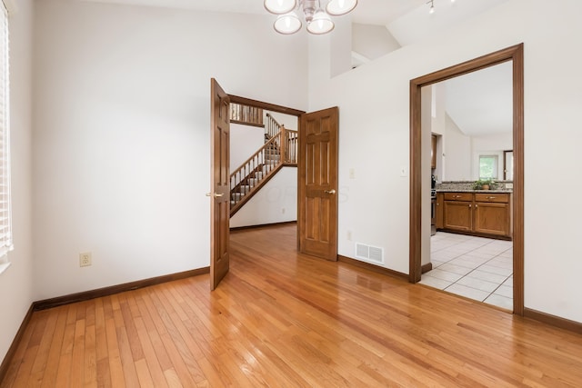 5839 Castleknock Rd, Dublin, OH 43016 - unfurnished room with light wood finished floors, stairway, vaulted ceiling, a chandelier, and baseboards