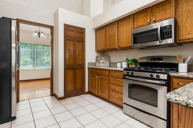 5839 Castleknock Rd, Dublin, OH 43016 - kitchen with appliances with stainless steel finishes, brown cabinets, light tile patterned flooring, and light stone counters