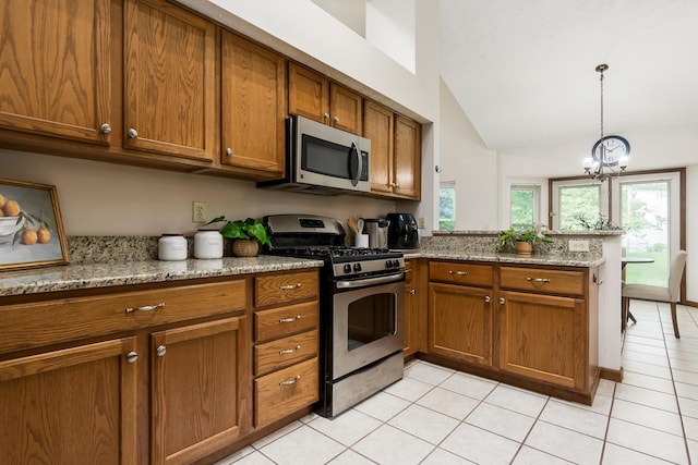 5839 Castleknock Rd, Dublin, OH 43016 - kitchen featuring appliances with stainless steel finishes, brown cabinets, a peninsula, lofted ceiling, and light tile patterned flooring