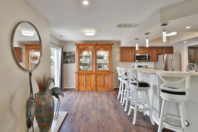 880 Village Brook Way, Columbus, OH 43235 - kitchen featuring appliances with stainless steel finishes, brown cabinets, a kitchen bar, light countertops, and dark wood-style floors