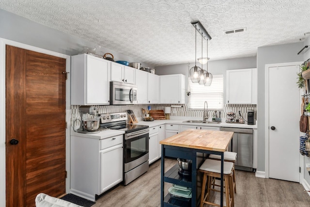 7765 Lantana Ave Unit 164, Blacklick, OH 43004 - kitchen featuring appliances with stainless steel finishes, a sink, light wood-type flooring, white cabinetry, and decorative light fixtures
