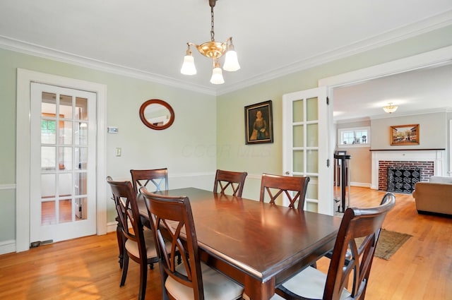 1875 King Ave, Columbus, OH 43212 - dining room featuring light wood-style flooring, a chandelier, a brick fireplace, and crown molding