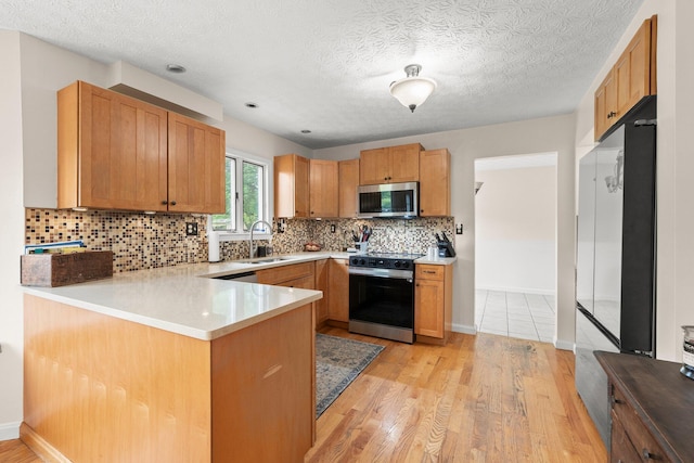 13682 Cobblestone Ln, Pickerington, OH 43147 - kitchen featuring stainless steel microwave, range, a sink, a peninsula, and light wood-style flooring