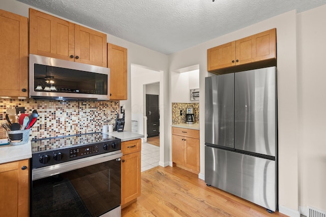 13682 Cobblestone Ln, Pickerington, OH 43147 - kitchen featuring stainless steel appliances, light wood-style flooring, light countertops, tasteful backsplash, and a textured ceiling
