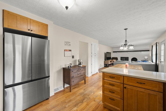13682 Cobblestone Ln, Pickerington, OH 43147 - kitchen with freestanding refrigerator, light wood-type flooring, a textured ceiling, open floor plan, and light countertops