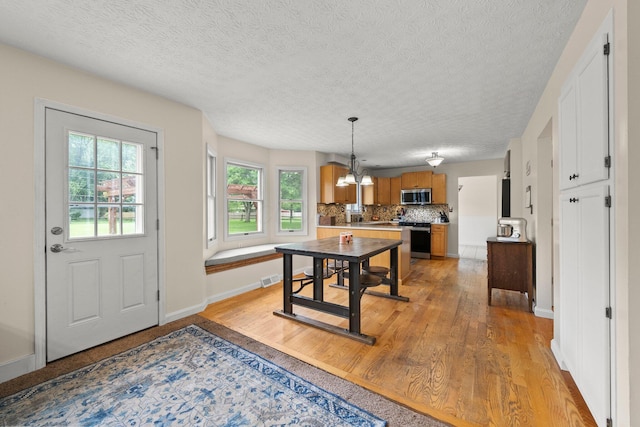 13682 Cobblestone Ln, Pickerington, OH 43147 - dining area featuring a chandelier, light wood-type flooring, a textured ceiling, and baseboards