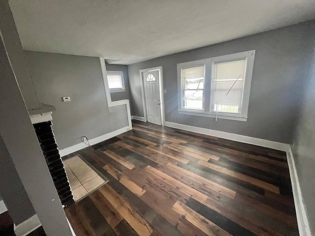 1403 Genessee Ave, Columbus, OH 43211 - unfurnished living room featuring dark wood finished floors, baseboards, and a brick fireplace