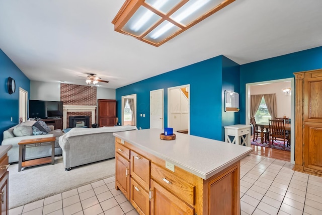 3902 Maple Grove Rd, Marion, OH 43302 - kitchen with light tile patterned floors, a ceiling fan, light countertops, a center island, and a fireplace