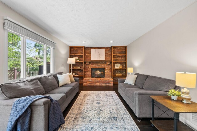 3567 Rochfort Bridge Dr, Columbus, OH 43221 - living room featuring dark wood finished floors, a textured ceiling, built in shelves, a brick fireplace, and recessed lighting