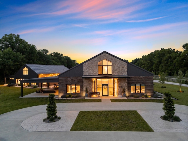 3226 Bean Oller Rd, Delaware, OH 43015 - back of house at dusk featuring stone siding, curved driveway, and a yard