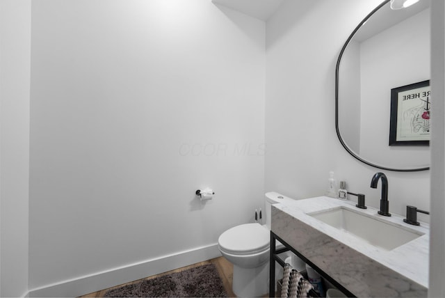 3226 Bean Oller Rd, Delaware, OH 43015 - half bathroom with toilet, baseboards, vanity, and wood finished floors