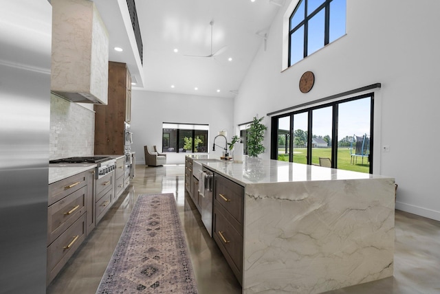 3226 Bean Oller Rd, Delaware, OH 43015 - kitchen featuring stainless steel appliances, a high ceiling, light stone counters, a spacious island, and decorative backsplash