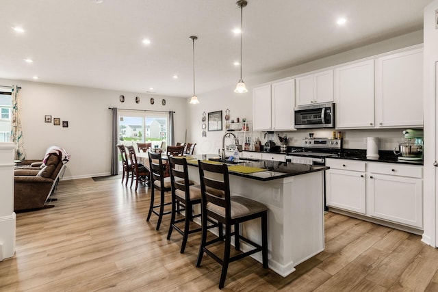 99 Hutchison St, South Bloomfield, OH 43103 - kitchen with stainless steel appliances, recessed lighting, light wood-style floors, dark countertops, and a kitchen bar