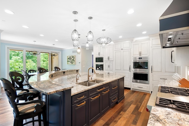 5633 Travis Pointe Ct, Westerville, OH 43082 - kitchen featuring a sink, white cabinetry, stainless steel double oven, a large island, and ornamental molding